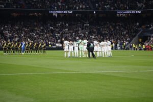 Jugadores del Real Madrid y del Rayo Vallecano guardando un respetuoso minuto de silencio abrazados en el centro del campo.
